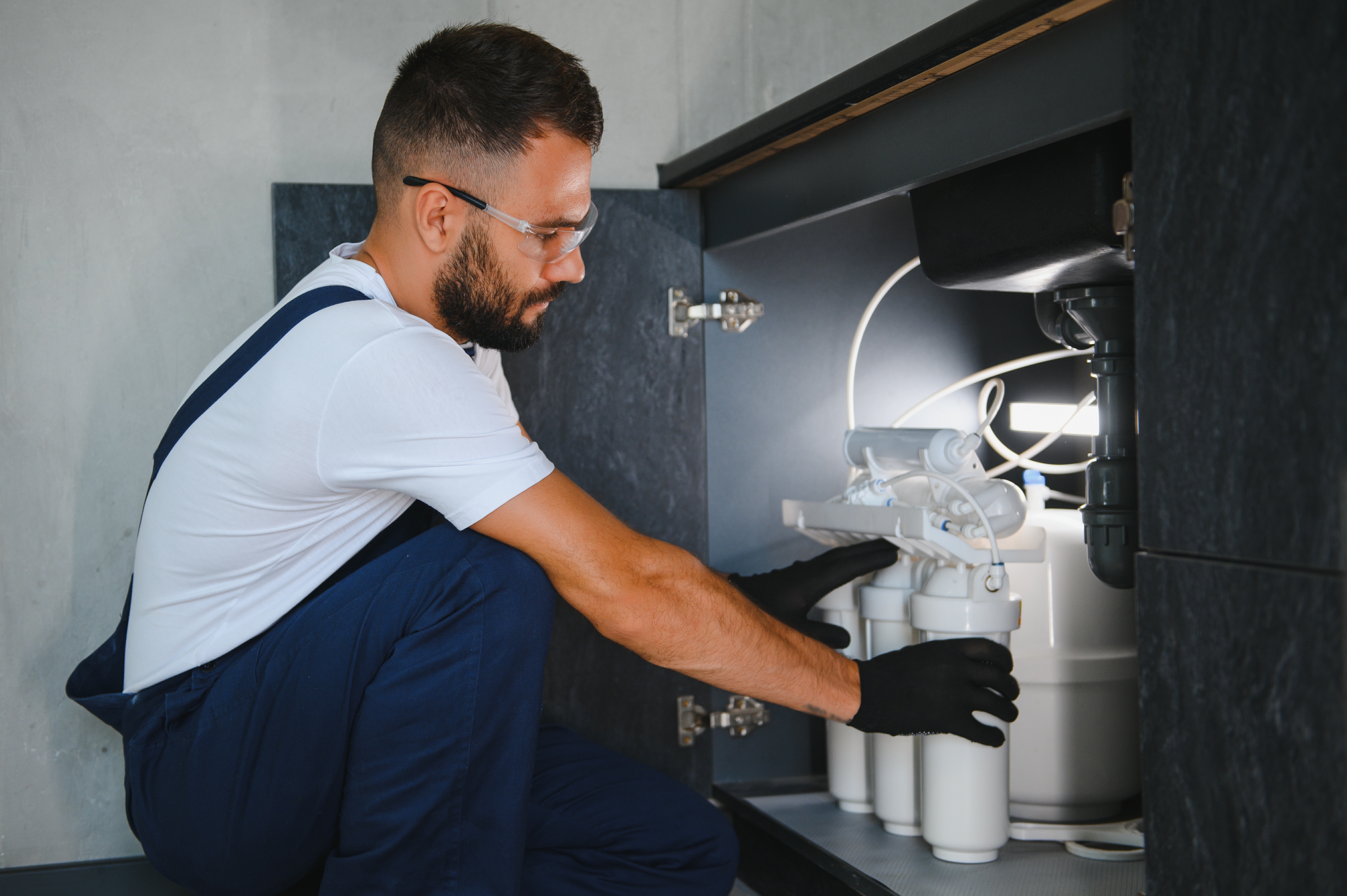 Technician installing reverse osmosis system under kitchen sink